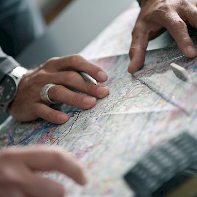 Hände und Geodreieck auf einer Flugkarte