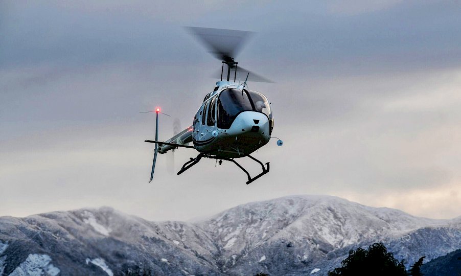 Hubschrauber vor schneebedeckten Bergen